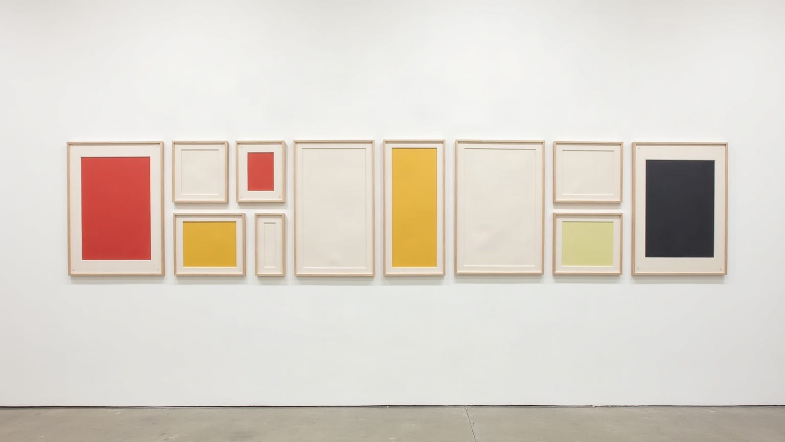 Ten empty picture frames of different sizes hung across a gallery wall